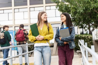İki üniversite öğrencisi kız üniversite kampüsünde dışarı çıkıp üniversite konferansından çıkıyorlar.