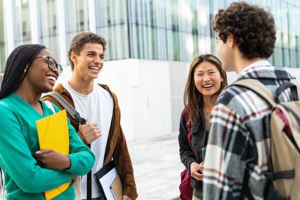 Группа из четырех студентов собирается перед зданием университета после лекции, разговаривая весело