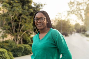 Şehir parkında gülümseyen gözlüklü Afrikalı Amerikalı kadın - Kolej öğrencisi kız 