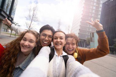 Genç arkadaşlarının portresini yapan bir kız modern şehrin dışında cep telefonuyla selfie çekiyor. 