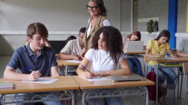 Sevecen öğretmen öğrencilere Kolej Lisesi 'nde yazma alıştırması öğrenmelerine yardım ediyor.