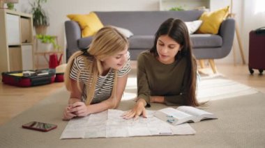 Kız arkadaşlar harita ve turist rehberiyle tatil yapmayı planlıyorlar.