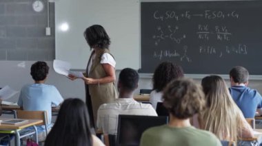 Bilim ve teknoloji okuyan üniversite öğrencilerine sınav yapan kadın profesör.