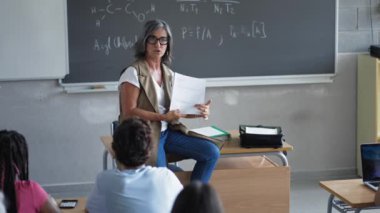 Kadın öğretmen, lise öğrencilerine ödev sınavını, Teknoloji ve Fen Bilgisi 'ni anlatıyor.