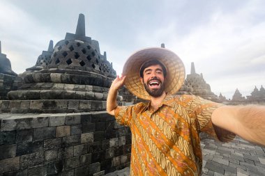 Endonezya 'da gezerken, Borobudur' un ünlü Budist anıtını ziyaret ederken selfie çeken mutlu genç turist.