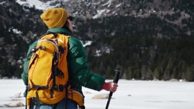Dişi yürüyüşçü, kar ormanı dağ manzarasını inceliyor. 