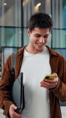 Erkek öğrenci üniversitede sınav sonuçları için cep telefonu kullanıyor