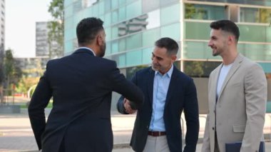 Bir grup İspanyol ve Hintli iş adamı ofis toplantısında tokalaşıyor. Şehirde üç işadamı anlaşma imzalıyor.
