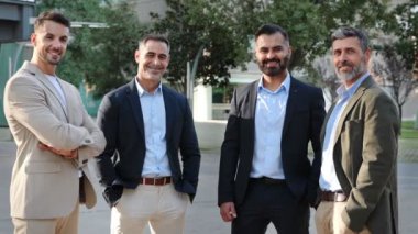 Şehirde gülümseyen zarif iş adamlarının toplu portresi. İspanyol, Orta Doğu ve Hintli erkek iş adamları