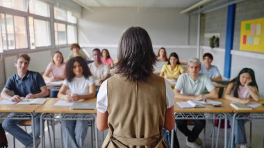 Üniversite öğrencileri lisede yetişkin kadın öğretmenlerin konuşmalarını dinliyorlar.