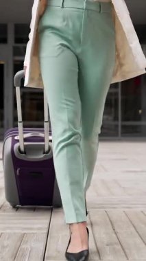 İş gezisinden sonra otelden havaalanına giderken yanında bavul taşıyan genç, profesyonel bir kadın.