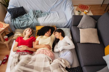 Genç bayan arkadaşlar evde pijamalarıyla yatıp eğleniyorlar.