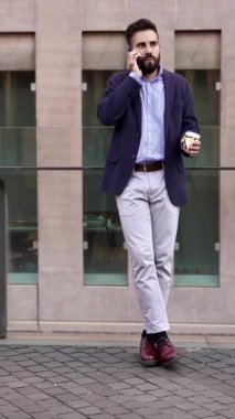 Genç işadamı cep telefonuyla dışarıda iş arkadaşlarıyla konuşuyor.