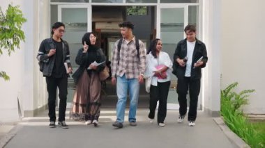 Endonezya Üniversitesi öğrencileri kolej kampüsünün önünde yürüyor, kitap tutuyor, ders ve sınavlardan sonra gülüyor.