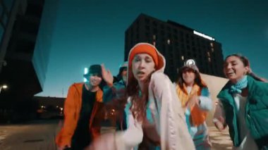 Geceleri şehirde bir grup modaya uygun genç arkadaşla dans eden acayip kız dansçı. 