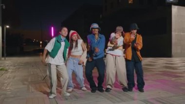 Bir grup havalı genç arkadaş gece dans eden müzik videosu dans partisinde kameraya bakıyorlar.