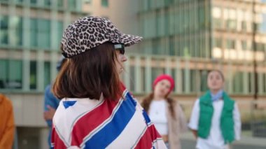 Şehirde modern arkadaşlarla poz veren ve dans eden modaya uyan Latin bir kadın.