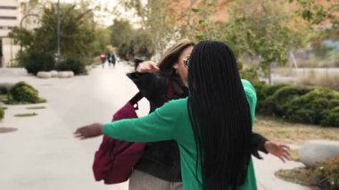 Şehirde birbirine sarılan iki mutlu kız arkadaş. Kadınlar parkta buluşmayı kucaklıyor. 