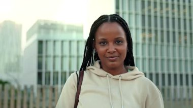 Afrika kökenli Amerikalı üniversite öğrencisinin portresi kameraya bakıyor ve üniversitenin dışında gülüyor.