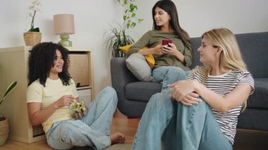 Bir grup mutlu kız arkadaş evde yemek yerken konuşuyor. 