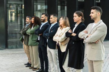 Business Company takımı, modern ofis binalarının önünde el ele tutuşmuş bir şekilde ayakta duruyor.
