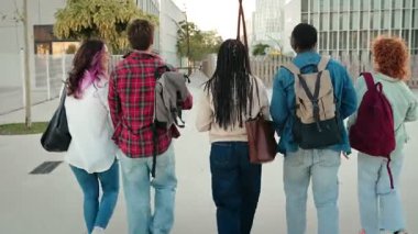 Üniversite binasına doğru yürüyen bir grup üniversiteli arkadaşla derslere giren Afrikalı Amerikalı öğrenci.