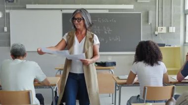 Lise öğrencilerine sınav kağıdı veren bayan öğretmen teknoloji ve bilim öğreniyor. 
