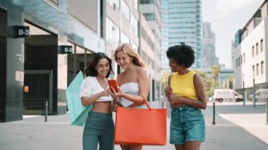 Cep telefonuna bakan çeşitli bayan arkadaşlar şehirde alışveriş yaparken eğleniyor.