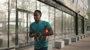 Siyah adam, şehirde çalışan akıllı saat uygulamasında fitness performansını kontrol ediyor.