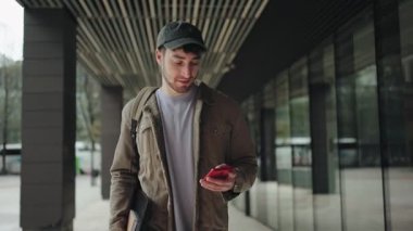 Şehirde, modern iş alanında cep telefonu uygulaması kullanan genç bir öğrenci.