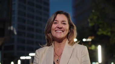 Geceleri şehirde gülümseyen sarışın, olgun bir iş kadınının portresi.