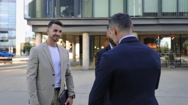 İş adamları modern ofis binasının önünde el sıkışıyor ve konuşuyorlar. Hindistan ve İspanya işbirliği