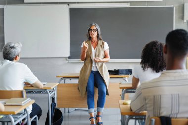 Olgun kadın öğretmen üniversite sınıfındaki bir grup lise öğrencisine motivasyon dersi veriyor.