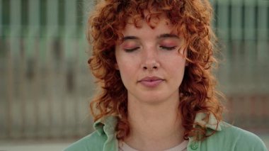 Genç kızıl saçlı bir kadının portresi yavaşça gözlerini açıyor ve kameraya bakıyor.