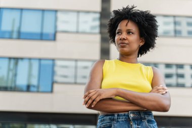 İyimser bir portre genç Afrikalı Amerikalı kadın kentte duruyor ve kendinden emin bir ifadeyle yan tarafa bakıyor.