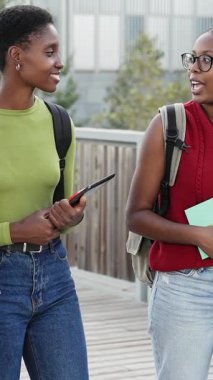 Kampüste yürüyen ve konuşan iki Afrikalı Amerikalı üniversite öğrencisi.