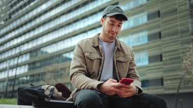 Genç adam cep telefonu uygulaması kullanıyor, internette geziniyor, sohbet ediyor, video izliyor ya da oyun oynuyor