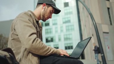 Kampüs parkında dizüstü bilgisayar kullanan genç bir üniversite öğrencisi.