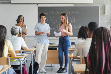 Lise öğrencileri kimya projelerini sınıf arkadaşlarının ve öğretmenlerinin önünde sunuyorlar. Eğitim ekibi çalışması