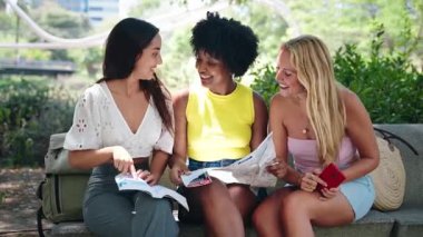 Tatil gezileri sırasında haritaya, rehbere ve cep telefonuna danışan genç kadın turistler