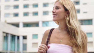 Şehir merkezinde gülümseyen ve gülen zarif sarışın bir kadın.