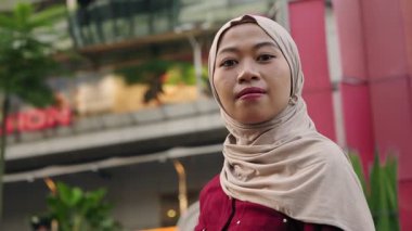 Endonezyalı bir kadın, Müslüman tesettüre bürünmüş, Jakarta caddesinde kameraya gülümsüyor.