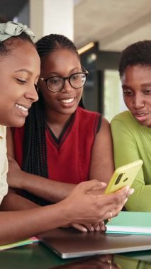 Afrikalı Amerikalı üniversite öğrencileri sosyal medya içeriğini paylaşmak için cep telefonu uygulamasını birlikte kullanıyorlar