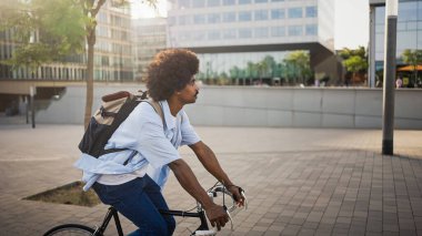 Sırt çantalı, bisiklet süren sıradan bir Afrikalı Amerikalı sabah işe gidiyor.