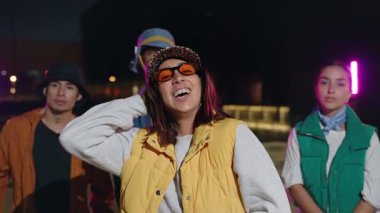 Neşeli Latin kadın geceleri modern funky tarzında moda arkadaşlarıyla poz veriyor.