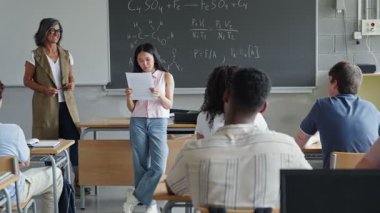 Lisedeki sınıf arkadaşlarına ve öğretmenlerine Asyalı kız öğrenci okuma projesi sunumu