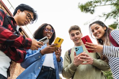 Sosyal medyada içeriği paylaşmak için cep telefonu uygulamasını kullanan bir grup öğrenci