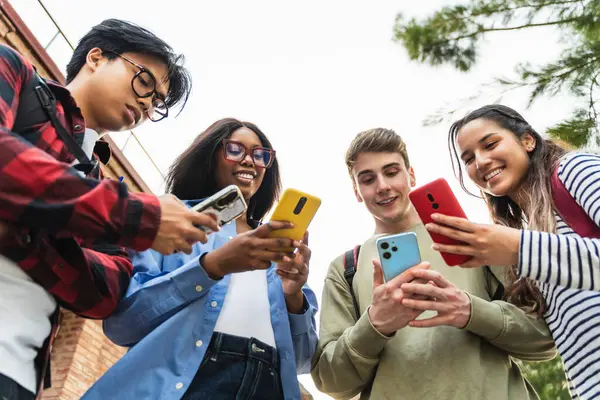 Sosyal medyada içeriği paylaşmak için cep telefonu uygulamasını kullanan bir grup öğrenci