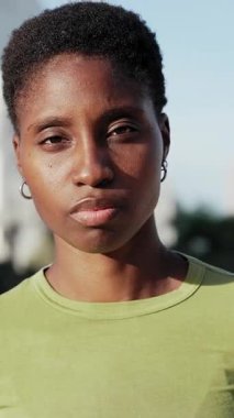 Şehirde gülümseyen kısa saçlı siyahi bir kadının portresi.