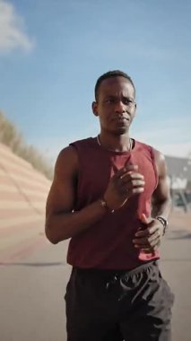 Kararlı Afro-Amerikan atleti açık havada koşuyor.